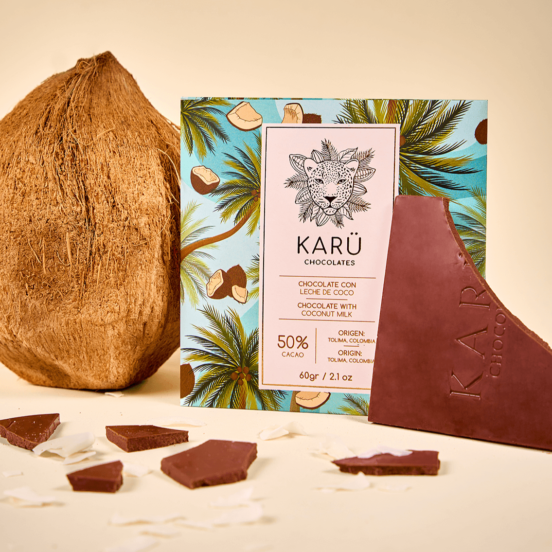 Un coco fresco entero, con la caja de chocolate con leche de coco Karü en el centro y la barra partida en trozos al costado derecho.
