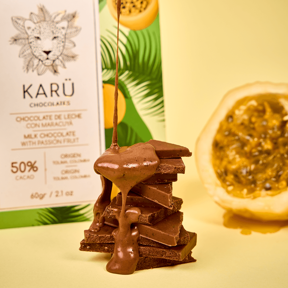 Trozos apilados de chocolate de maracuyá Karü con chocolate derretido chorreando, una caja del producto al fondo y una fruta de maracuyá fresca como decoración.