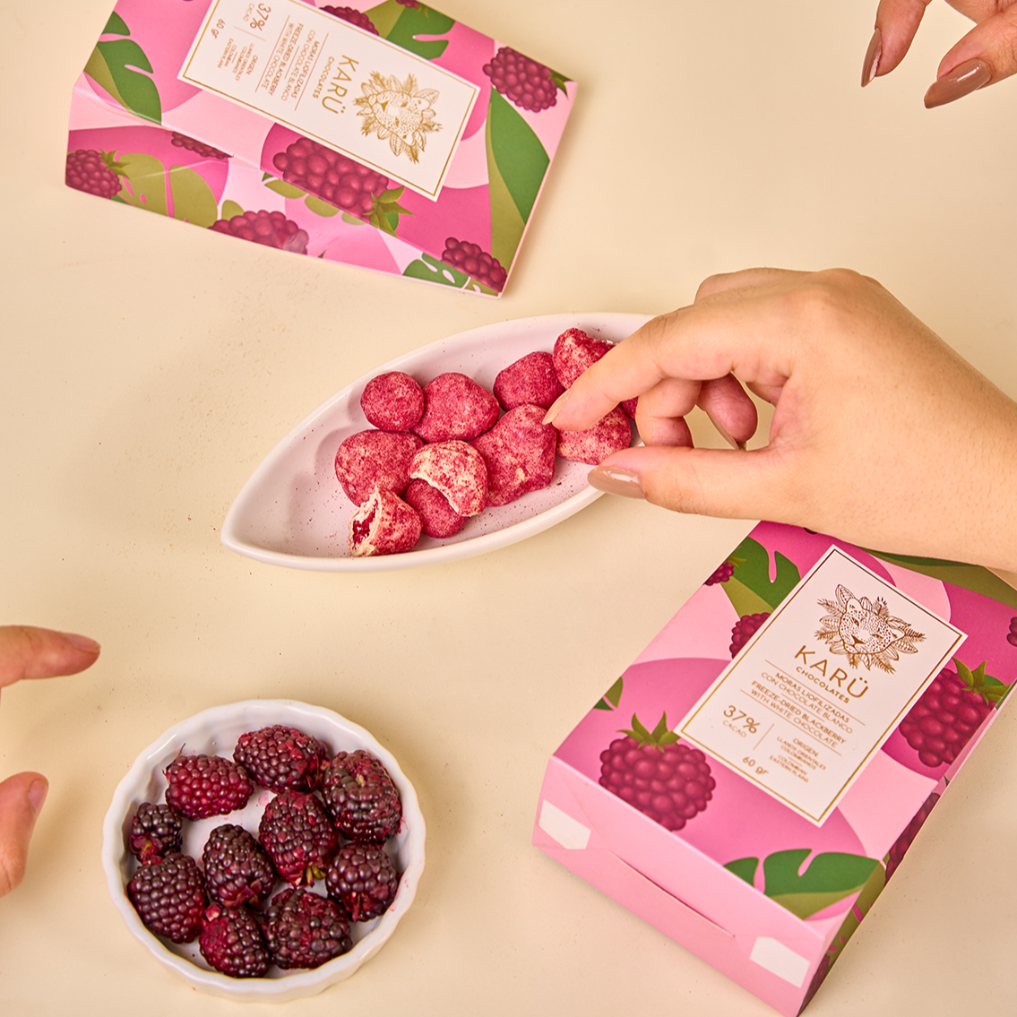 Cajas de moras cubiertas de chocolate blanco Karü, con moras frescas y chocolates en un recipiente al centro de la imagen.
